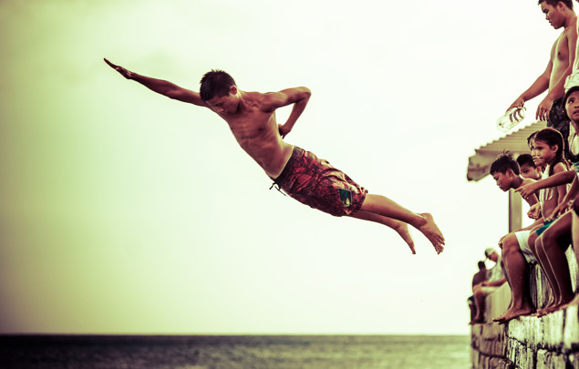 Hawaiian kids jumping off the wall into the ocean